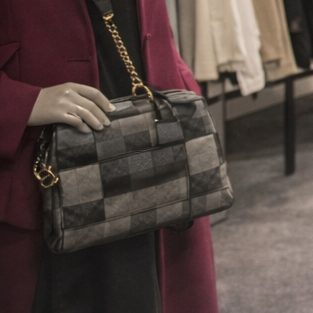 Schwarze Handtasche mit kariertem Muster, elegant in einer Boutique gehalten.